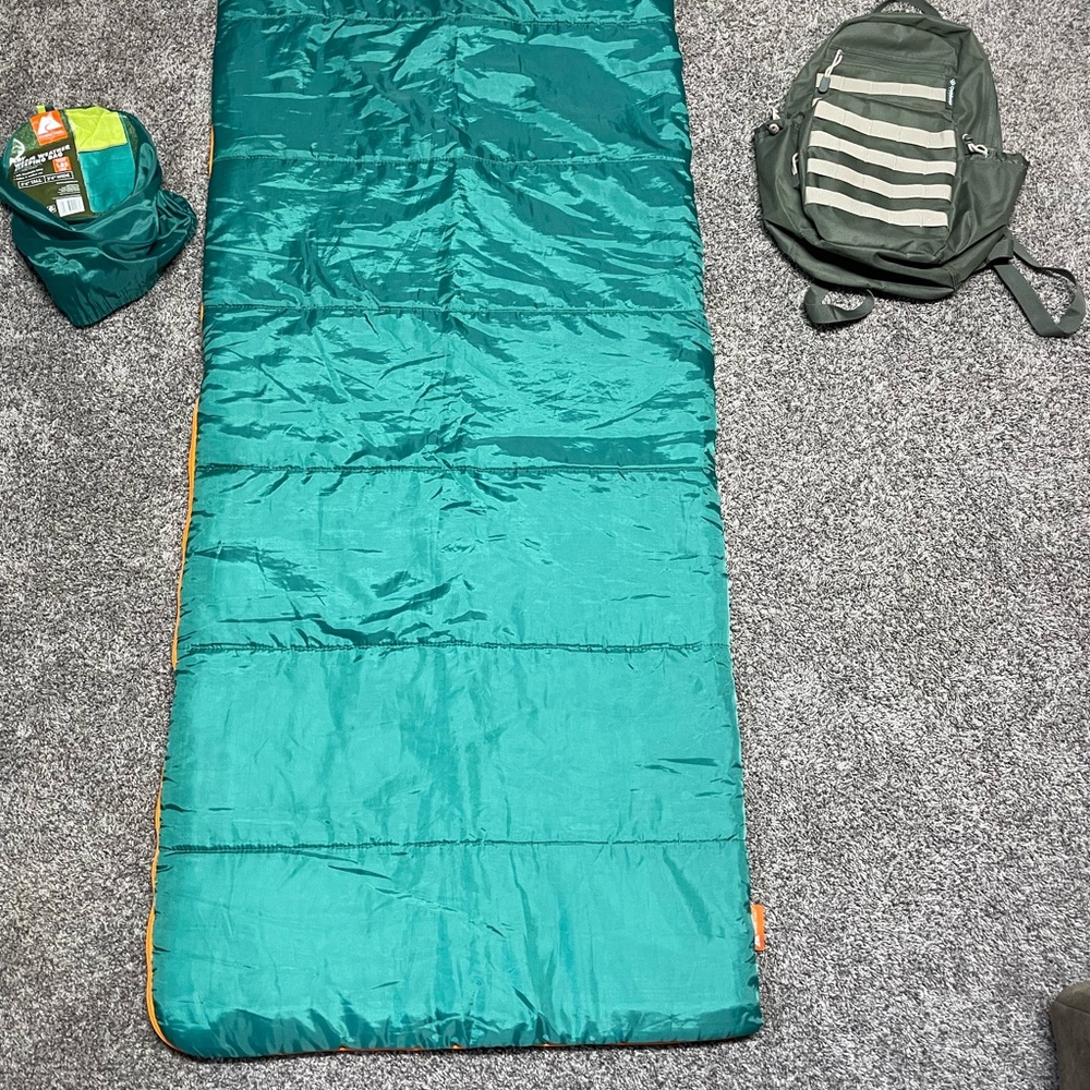 Ozark Trail Teal Sleeping Bag with Orange Accent and Green hiking backpack.